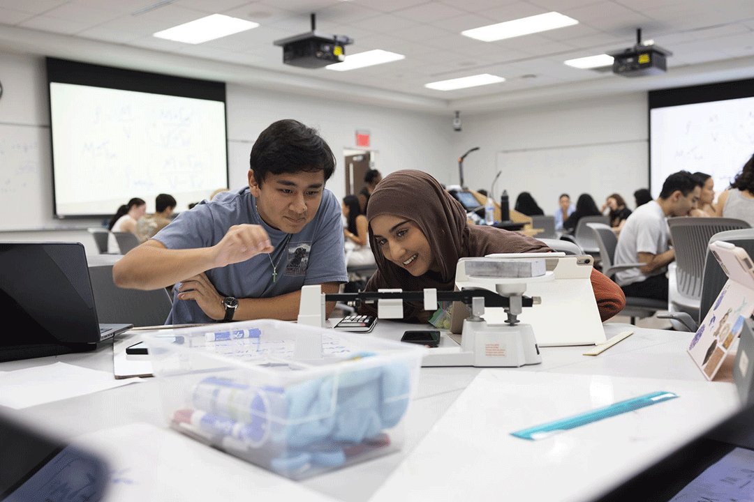 Two students seated together at a table in a Physics scale-up lab 
