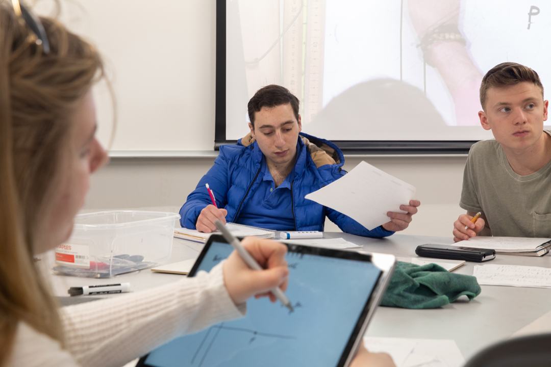 three physics students writing on personal tablets