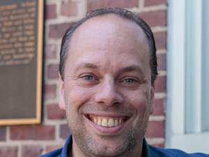 Alexander Van der Horst sitting outside a brick building in a blue collared shirt